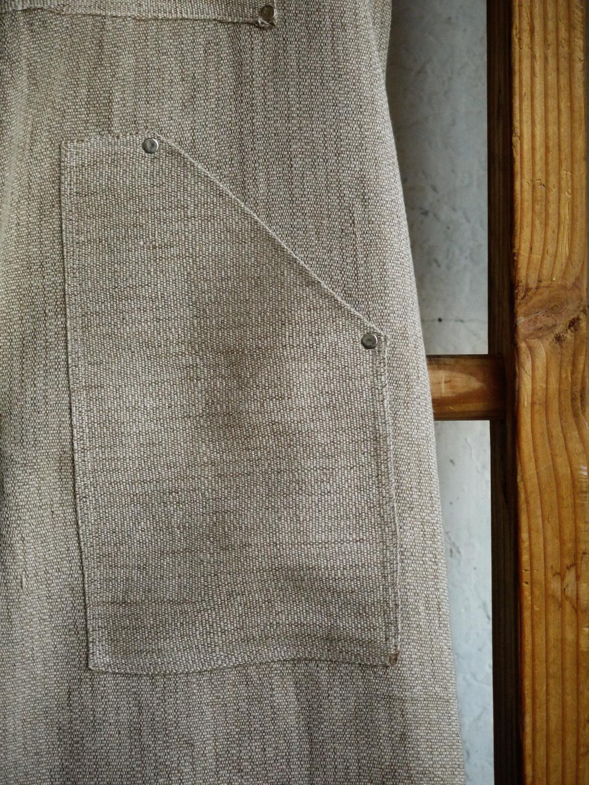 one of the patch pockets, affixed to the leg with small metal rivets. the grain of the canvas runs horizontally, opposed to the vertical grain on the rest of the garment.