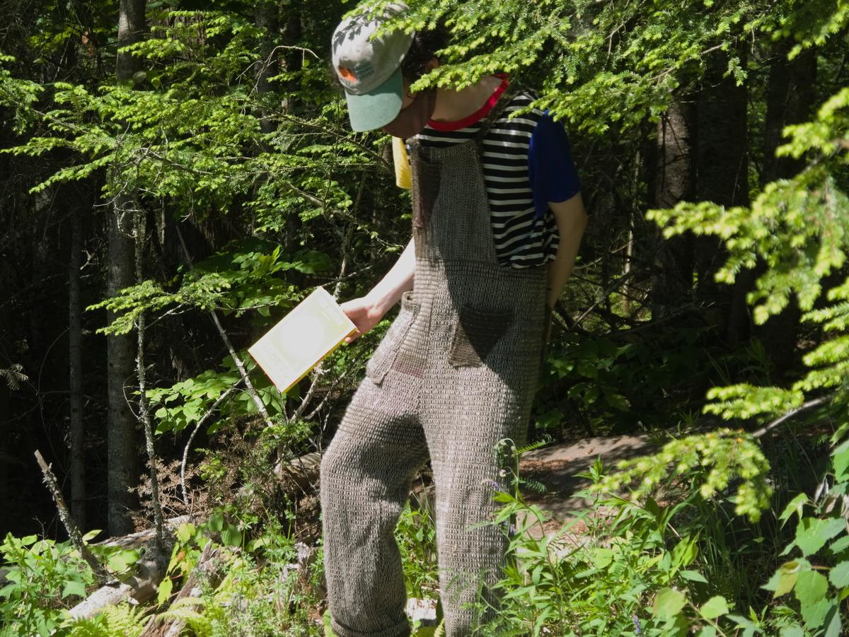 the figure standing up in the same place, showing the overalls' textural stripes and pockets.