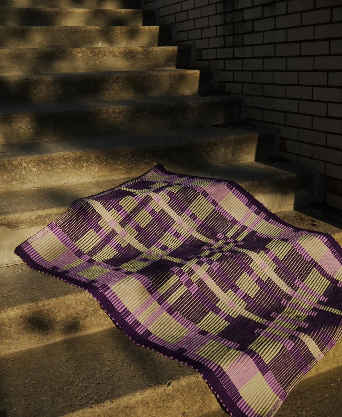 rug gracefully draped on concrete stairs, sun-dappled