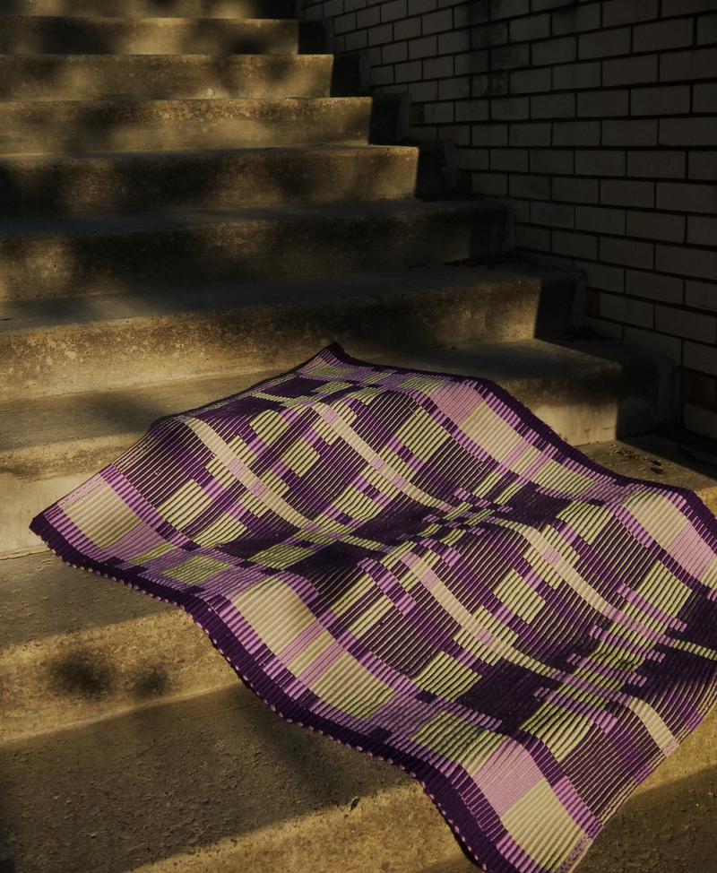 rug gracefully draped on concrete stairs, sun-dappled.
