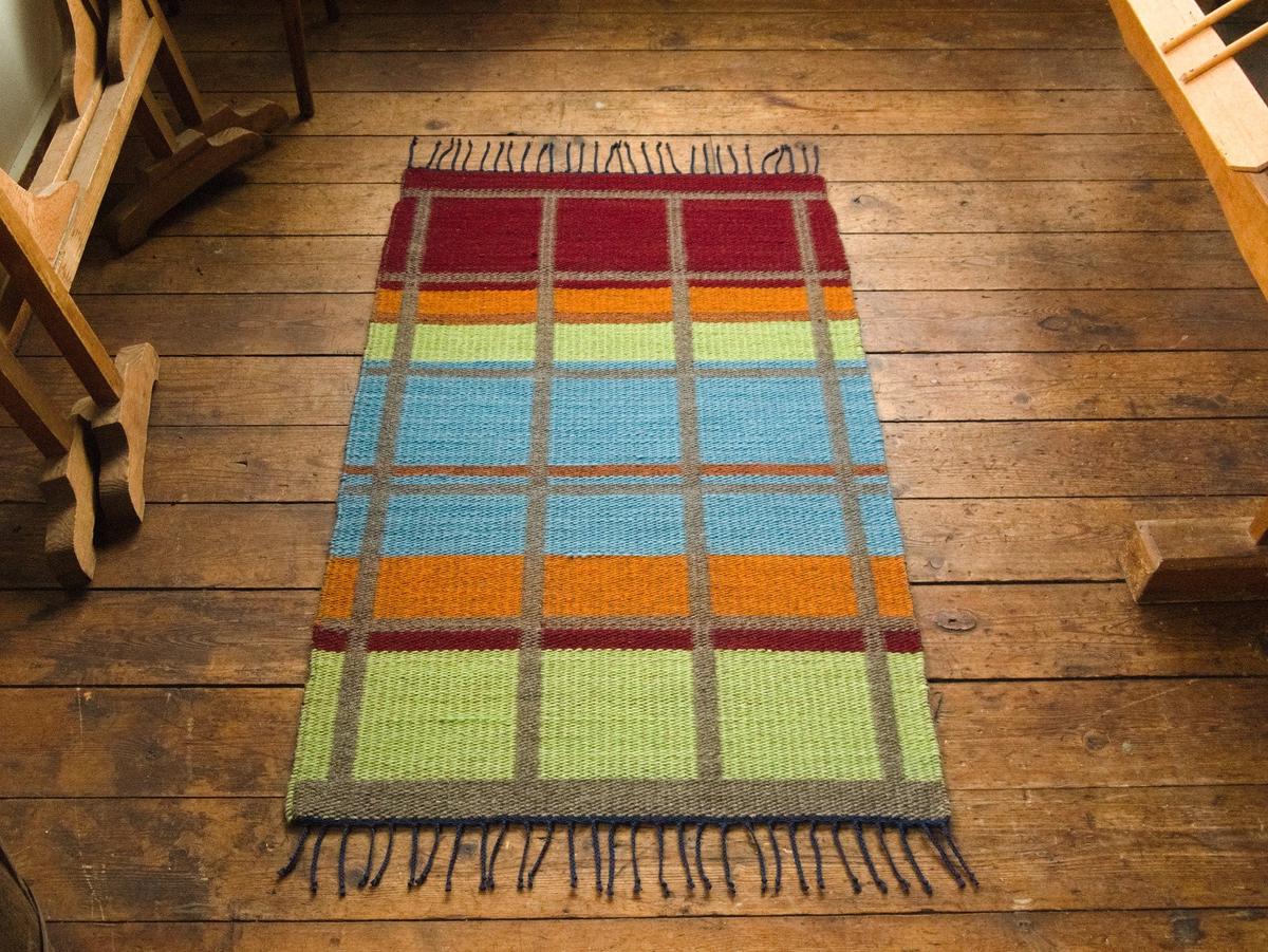 back side of the rug, showing bright blocks of color with grey in between.