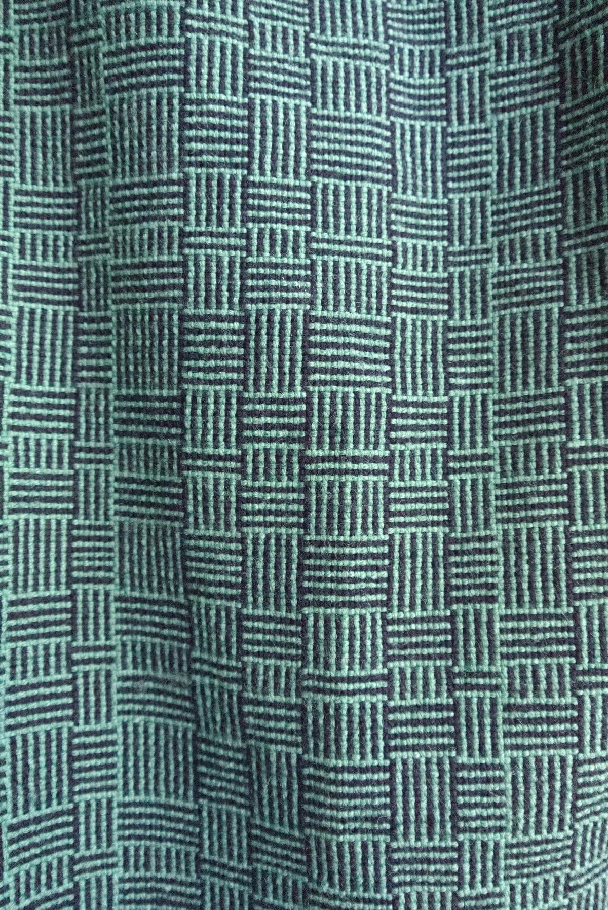 wider view of the pattern. the rows and columns look rigid and architectural, but the cloth beneath ripples softly.